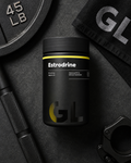 Black supplement container labeled 'Estrodrine' with a gym weight and towel in the background.