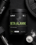 Black container of Switch Nutrition Beta Alanine supplement on a dark surface with fitness equipment.