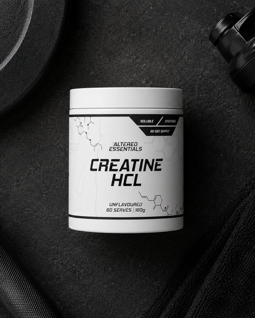 Container of Altered Essentials Creatine HCL on a dark surface with fitness equipment.