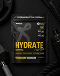 Black and yellow supplement package labeled 'Hydrate' on a dark background with fitness equipment.