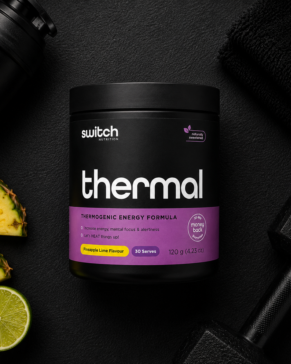 Black supplement container labeled 'switch thermal' on a dark surface with a pineapple, lime, and black shaker.