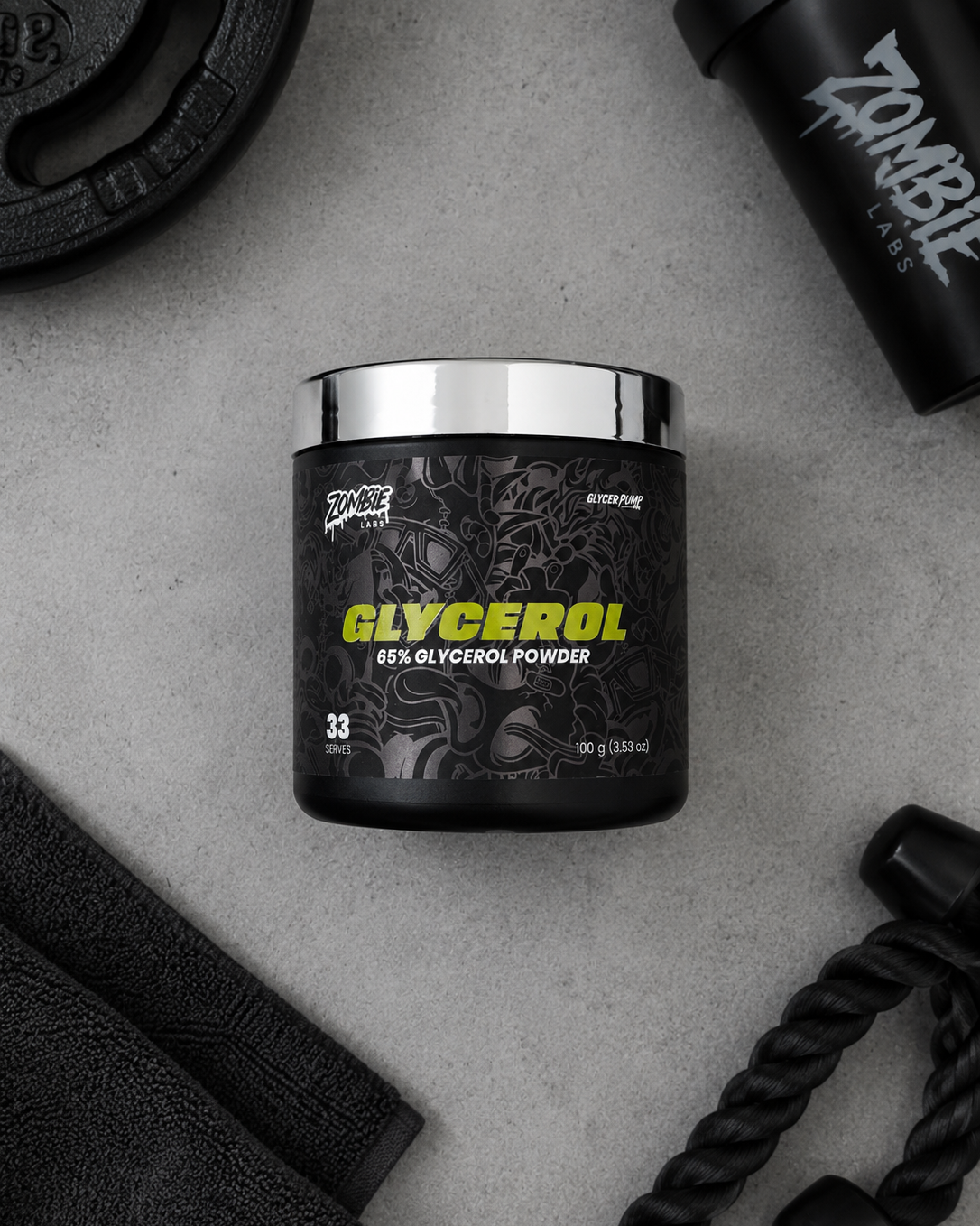 A black tub of Spire Labs Glycerol 69% Glycerol Powder with a shiny silver lid, styled on a gray concrete background with gym accessories like a shaker bottle, weight plate, and resistance bands.