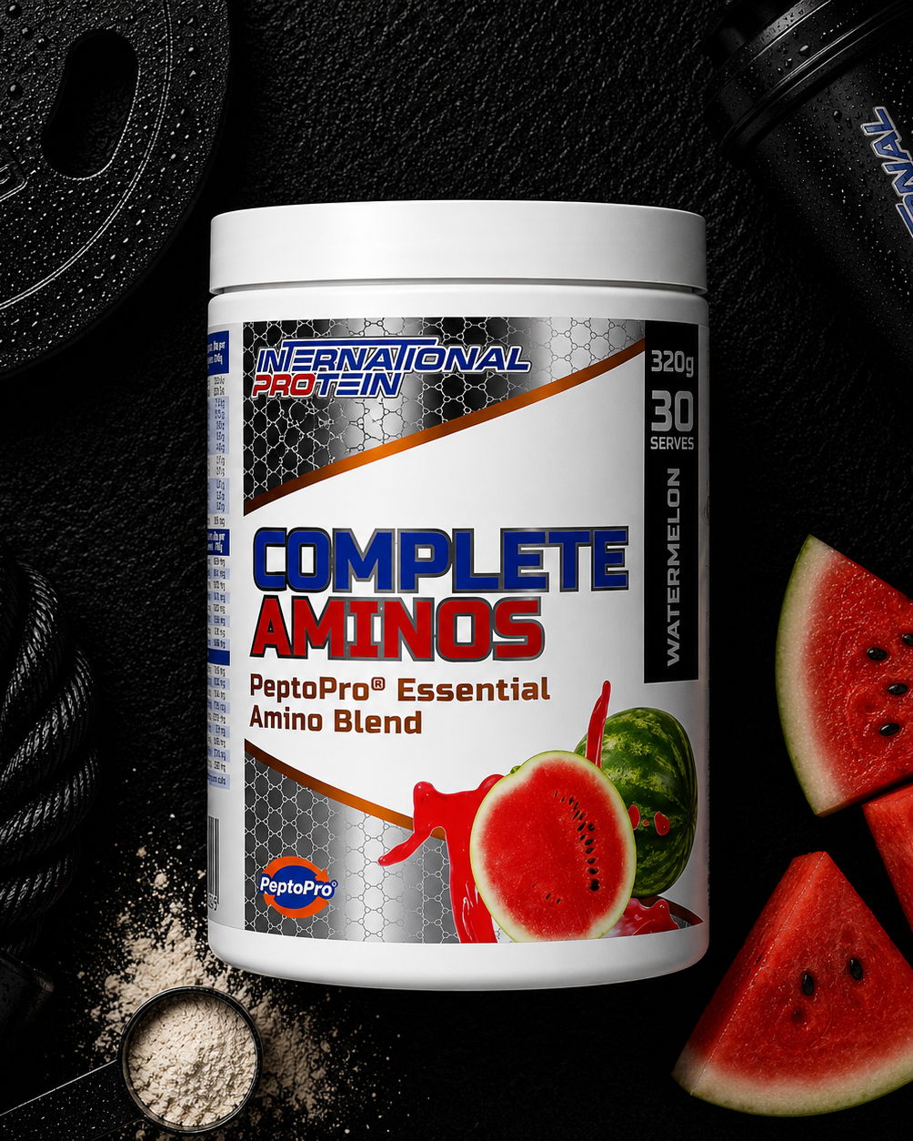 International Protein Complete Aminos supplement container with watermelon flavor on a black background with gym equipment and watermelon slices.