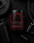 Black supplement container with red text on a dark background with fitness equipment.