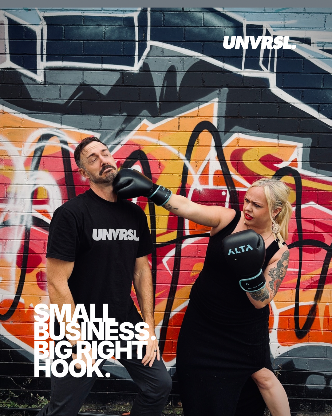 Two people in black shirts with 'UNVRSL' branding in front of a graffiti-covered wall.
